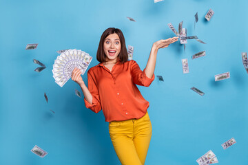 Portrait of attractive cheerful girl holding throwing wasting cash having fun isolated over bright blue color background