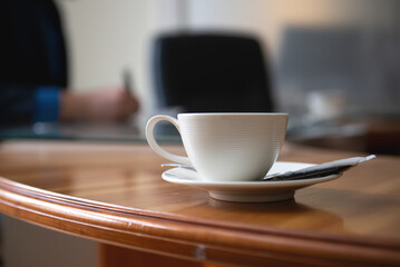 white cup of coffee on an office desk, business meeting concept