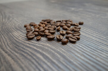 The coffee beans lying on the table with wooden texture.
Close up image of the coffee beans on the wooden background.