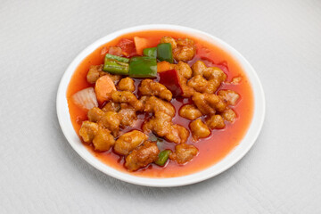 closeup of sweet and sour pork, typical dish of Chinese food on a white tablecloth