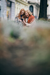 A granddaughter teaching her granny how to use mobile phone.