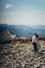 Naklejka premium A girl in a poncho and a dress walks along a mountain range