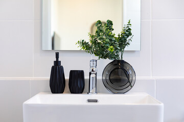 The sink in a bathroom is decorated with plants.