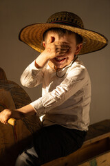 Niño juguetón feliz sonriente expresivo posando con sombrero campesino vaquero disfrutando - obrazy, fototapety, plakaty