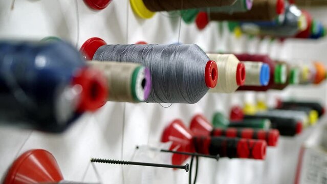 threads of different colors hang on wall. Atelier for tailoring clothes or car interiors made of fabric and leather, special closet with large number of threads of different thicknesses and sizes.