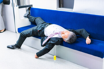 電車内で寝転ぶ中年男性