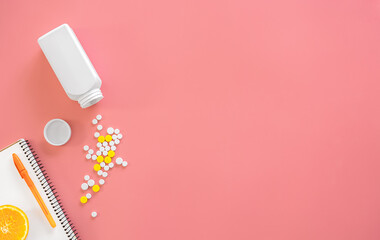Scattered pills on a pink background, flat lay.