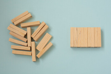 Fallen wooden blocks and a stack of orderly stacked blocks. The concept of business leadership