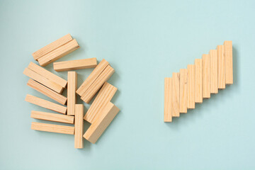 Fallen wooden blocks and a stack of orderly stacked blocks. The concept of business leadership