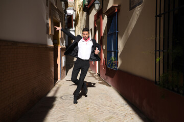 Obraz premium flamenco and gipsy man, dressed in black and white shirt and red polka dots handkerchief dancing flamenco in an alley in the streets of a mediterranean city. Flamenco cultural heritage of humanity.
