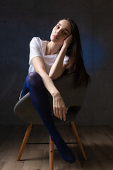 Portrait of a young brunette with long hair in the studio. Dramatic photo in dark colors.