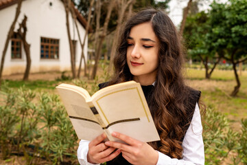 Reading, young woman sitting on park bench during work break reading her book, close-up model, selective focus on woman