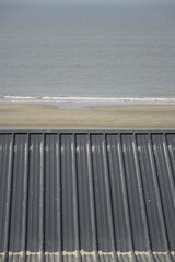 Top of black metal roof of beach hut over sandy North Sea beach, use: background, copy space (vertical), Zandvoort, North Holland, Netherlands - obrazy, fototapety, plakaty