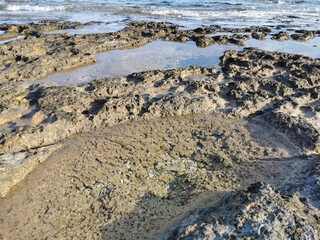 The coast of the Mediterranean Sea, long frozen lava, in the recesses of which water splashes.