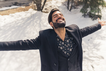 Stylish Latin well groomed man enjoying the winter snowy sunny day - dressed in black coat and suit. High quality photo