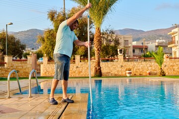 Man cleaning outdoor swimming pool, beautiful scenic view of nature background
