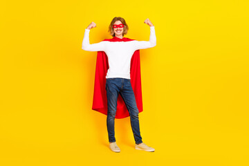 Fototapeta na wymiar Photo of lucky strong guy wear white shirt superhero outfit rising fists isolated yellow color background
