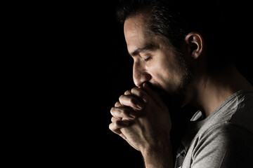 The man folding his hands in prayer to god on a black background. prayer to God for happiness and a...