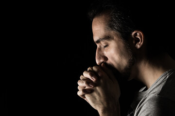 The man folding his hands in prayer to god on a black background. prayer to God for happiness and a...