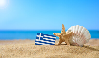 Fototapeta na wymiar Tropical beach with seashells and Greece flag. The concept of a paradise vacation on the beaches of Greece.