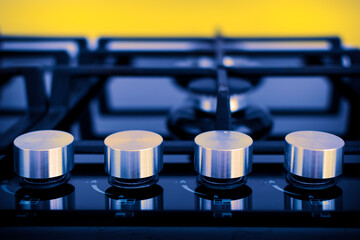 A gas cooker with regulators in close-up on a yellow background. Selective focus