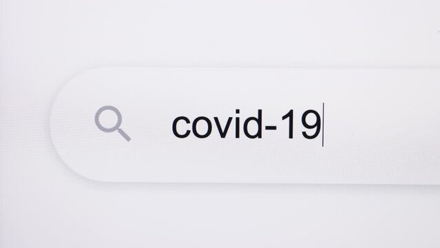 Close Up of typing COVID-19 into search bar on computer monitor. Virus or pandemic concept. How to, internet tips. Pixel art. Typing the word COVID 19 in the browser on pixelated computer screen