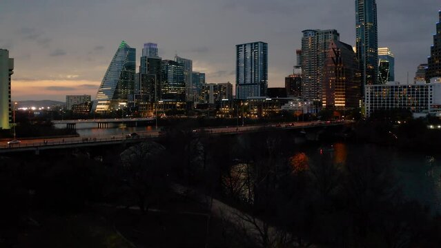 Downtown Austin Texas skyline in 2022 on beautiful evening sunset aerial pan down of congress bridge while bats fly out at night 4k