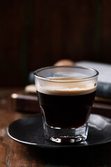 Coffee in glass cup on dark wooden background. Close up.