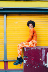 Young happy black woman fashionable sitting outdoor posing smiling having fun