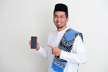 Moslem Asian man smiling while pointing to mobile phone screen that he hold