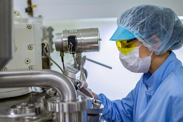 Pharmaceutical Machine Operator In Protective Clothing. Pharmaceutical Technician Works In Sterile Environment At Pharmaceutical factory. Female Worker In Pharmaceutical Industry.