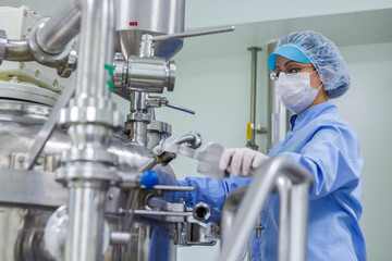 Pharmaceutical Industry Worker At Work In Sterile Environment. Preparing Machine For Work In Pharmaceutical Factory. Female Worker Wearing Protective Clothing In Pharmaceutical Plant.
