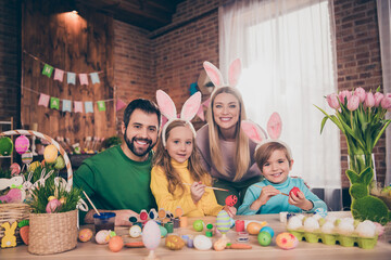 Photo of positive cheerful four people enjoy paint eggs prepare easter basket house indoors