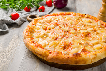 pizza Hawaiian with pineapple and chicken on grey wooden table macro close up