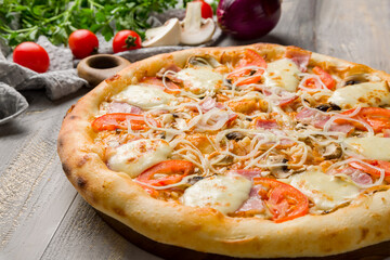 Italian meat pizza with onion and cheese on grey wooden table macro close up