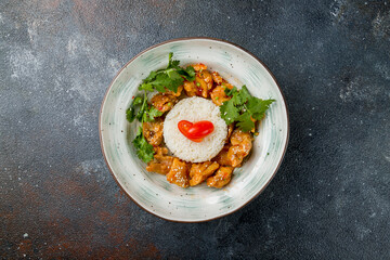 chicken in sweet and sour sauce with boiled rice on plate top view