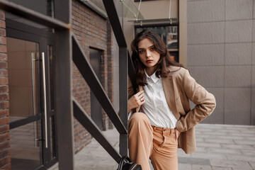  Tall stylish girl with oversized jacket posing near the railing and steps on the city background
