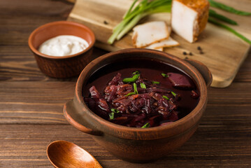 ukrainian red beetrootsoup, borscht with cream, onion, fat on the wooden table