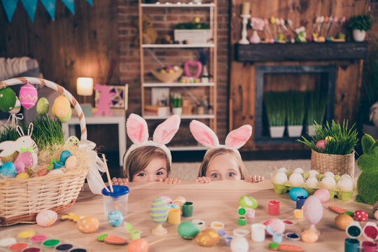 Photo of good mood funny positive kids hide behind table fooling around celebrate easter holiday paint many eggs