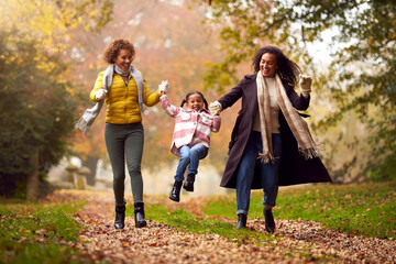 Multi-Generation Female Family Swinging Granddaughter On Walk Through Autumn Countryside Together