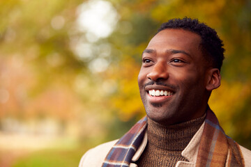 Fototapeta premium Head And Shoulders Portrait Of Man On Walk Through Autumn Countryside Against Golden Leaves
