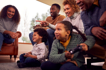 Multi-Generation Family Having Fun Playing Video Game In Lounge At Home Together