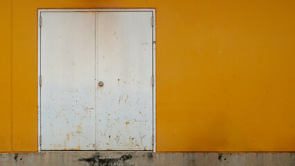 Old white metal door, orange wall Background.