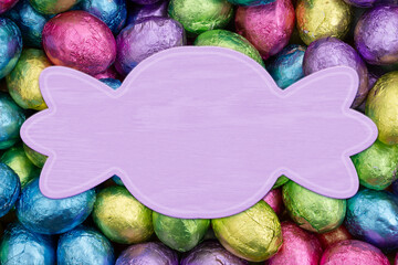 Blank pale purple banner with colorful shiny Easter eggs candy