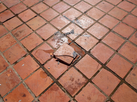 Cracked terracotta floor tiles. Broken clay tiles.