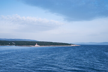 Obraz premium Seascape with blue sea and sky. Lighthouse on a coast.