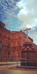 stone crucifix and church cathedral under blue sky with clouds