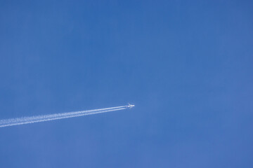 Passenger airplane and contrails against clear blue sky