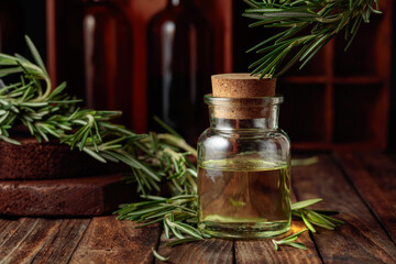 Rosemary essential oil or infusion on an old wooden table.