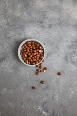 Roasted hazelnut. Hazelnut on plate on grey concrete background. Bulk hazelnut kernels. Hazelnut on a ceramic plate